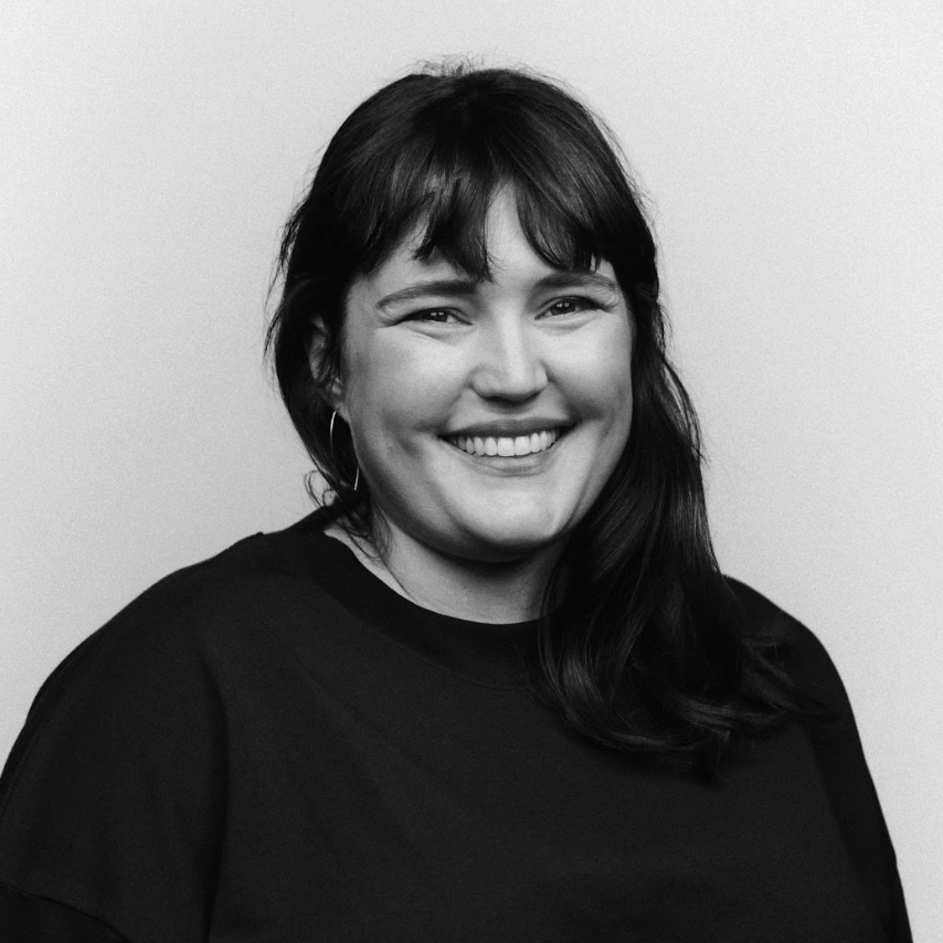 Photo en noir et blanc d'Ambre Langlois, elle est de face et elle sourit. Ses cheveux bruns, mi-long tombent sur son épaule gauche.